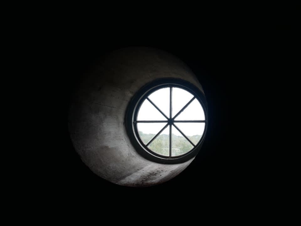 Mustassa seinässä pyöreä aukko, josta näkyy valoa.