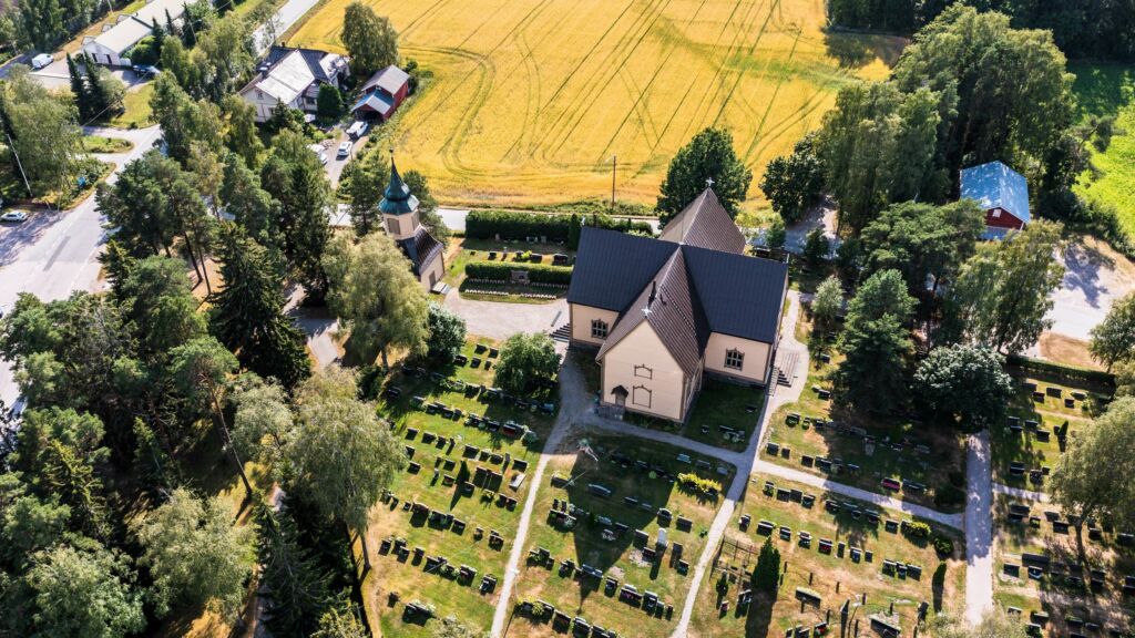 Puinen kirkko ja hautausmaa pellon vieressä.